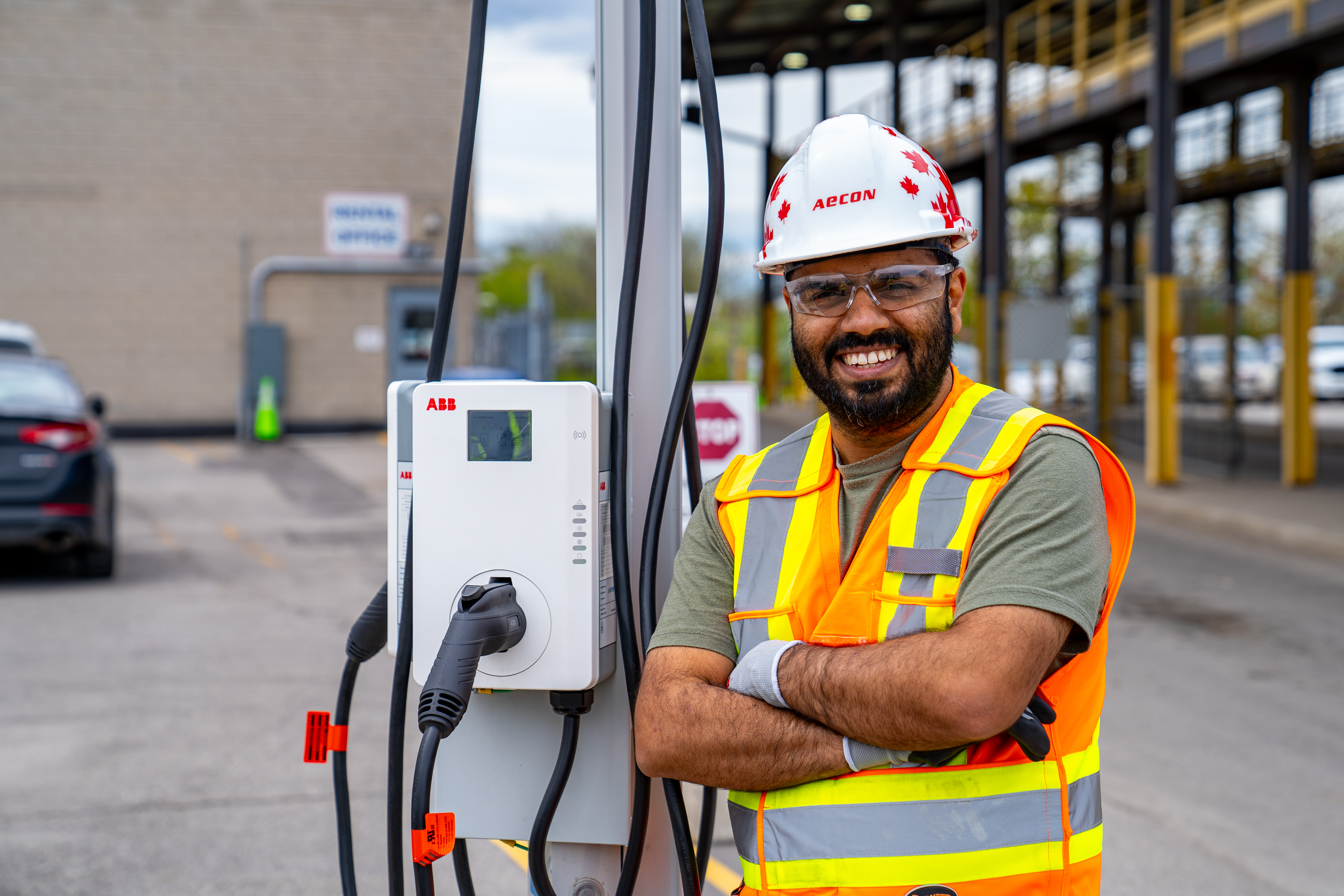 Aecon employee standing in front of EV vehicle charger